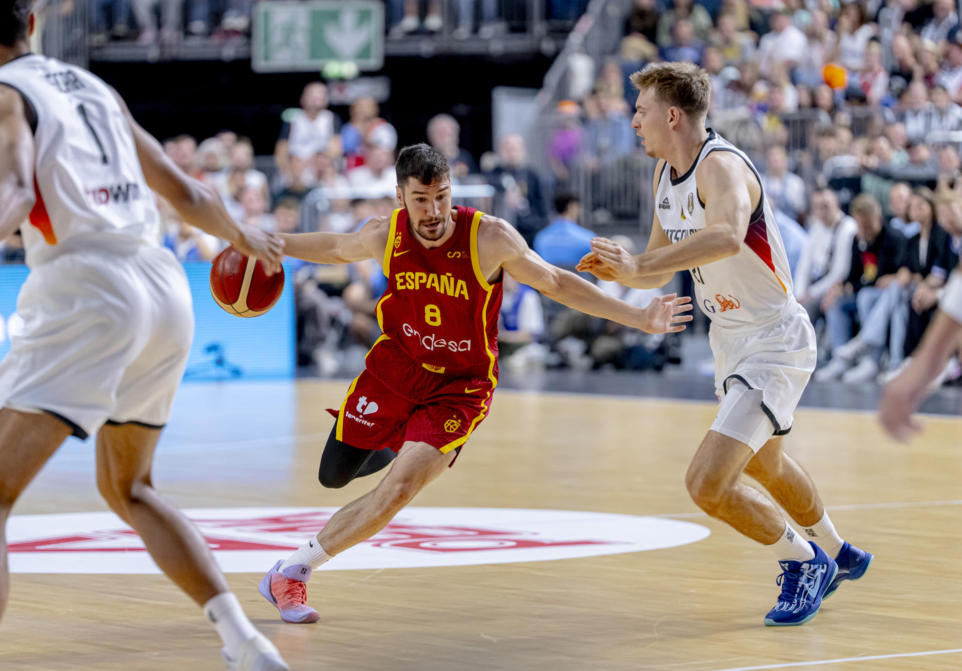 El escolta de España Darío Brizuela (c) supera al base de Alemania Justus Hollatz (d) durante el partido amistoso preparatorio para el Eurobasket 2025 celebrado este sábado en el Lanxess Arena de Colonia. EFE/FEB/Alberto Nevado