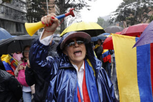Un seguidor del expresidente colombiano Álvaro Uribe marcha bajo la lluvia este jueves, en Bogotá (Colombia). EFE/ Mauricio Dueñas Castañeda