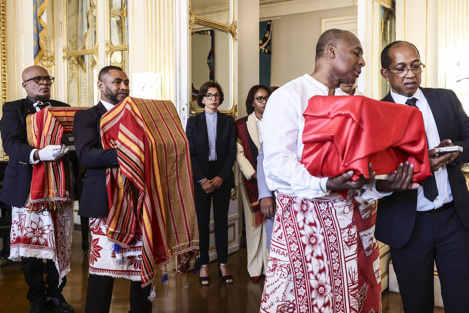 La Ministra de Cultura de Francia, Rachida Dati (C), sigue a un grupo de hombres llevando tres cajas que contienen restos humanos antes de la ceremonia para devolver tres cráneos originarios de Madagascar, pertenecientes a las colecciones públicas francesas, en el Ministerio de Cultura en París, Francia, 26 de agosto de 2025. (Francia) EFE/EPA/TERESA SUAREZ