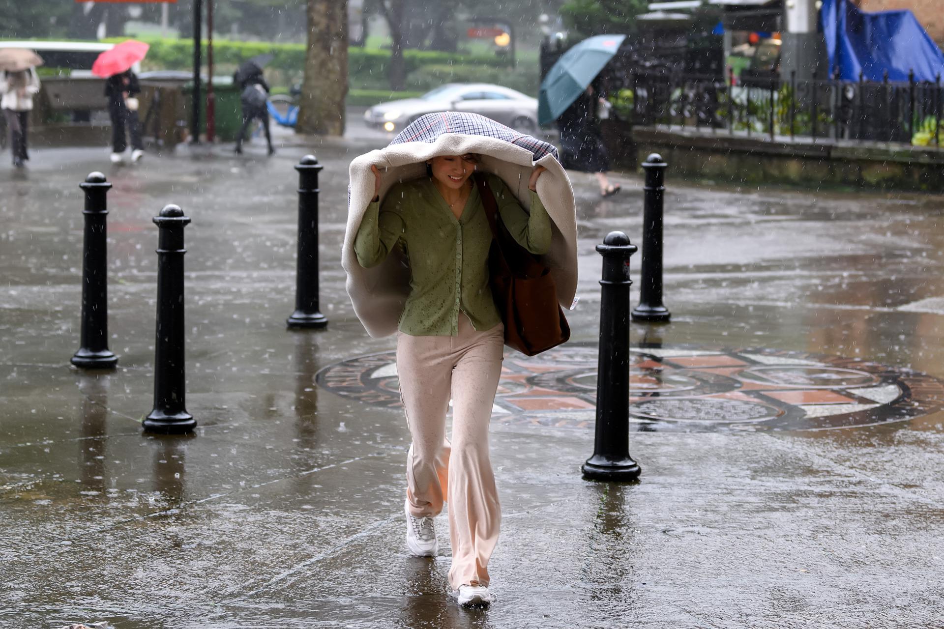 Una mujer trata de cubrirse de la lluvia en Sídney.
EFE/EPA/STEVE MARKHAM AUSTRALIA AND NEW ZEALAND OUT
