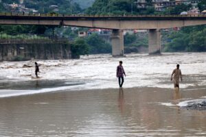 Varias personas se abren paso por una carretera anegada tras las inundaciones en Muzaffarabad, la capital de Cachemira administrada por Pakistán, este viernes 15 de agosto. EFE/EPA/AMIRUDDIN MUGHAL