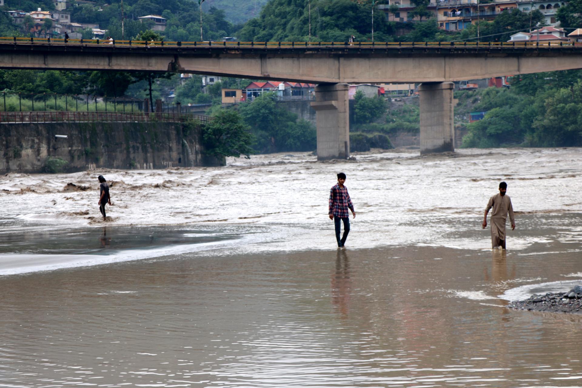 Varias personas se abren paso por una carretera anegada tras las inundaciones en Muzaffarabad, la capital de Cachemira administrada por Pakistán, este viernes 15 de agosto. EFE/EPA/AMIRUDDIN MUGHAL