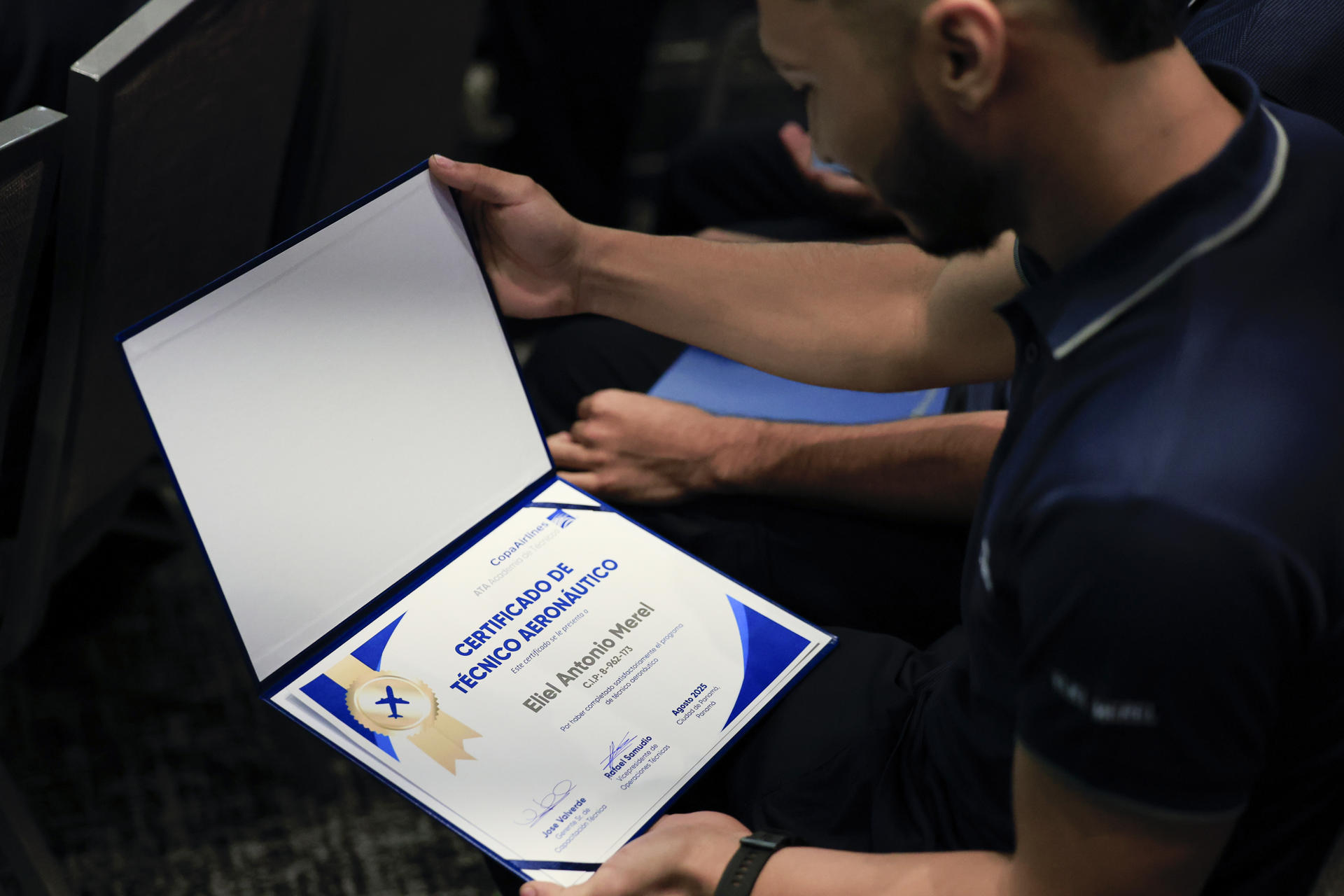 Un técnico aeronáutico de Copa Airlines fue captado este martes, 19 de agosto, al observar su certificado de graduación, durante una ceremonia, en Ciudad de Panamá (Panamá). EFE/Bienvenido Velasco
