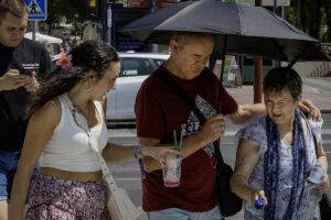 Varias personas se tapan con una sombrilla para resguardarse del sol mientras caminan por una calle en Sevilla este lunes. EFE /José Manuel Vidal