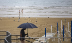 Dos jóvenes se meten al agua este martes en la playa de La Zurriola de San Sebastián. EFE/Javier Etxezarreta