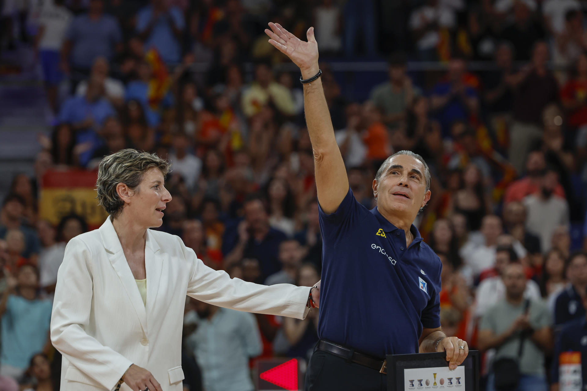 El entrenador de la selección española de baloncesto, Sergio Scariolo, y la presidenta de la Federación Española de Baloncesto, Elisa Aguilar (i), durante el homenaje recibido por el técnico al término del partido amistoso ante Alemania disputado este jueves en el Madrid Arena. EFE/Mariscal
