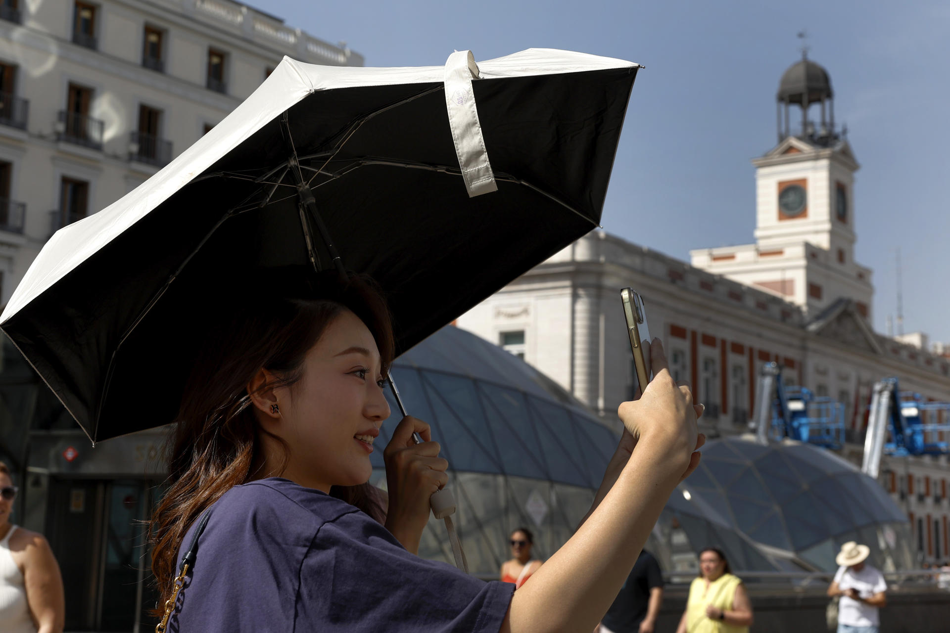 Turistas en la Puerta del Sol en Madrid este miércoles. La persistente ola de calor que mantiene en vilo a España alcanza este miércoles el 'ecuador' de este episodio térmico, con un ligero alivio en las temperaturas en gran parte del territorio.-EFE/Chema Moya