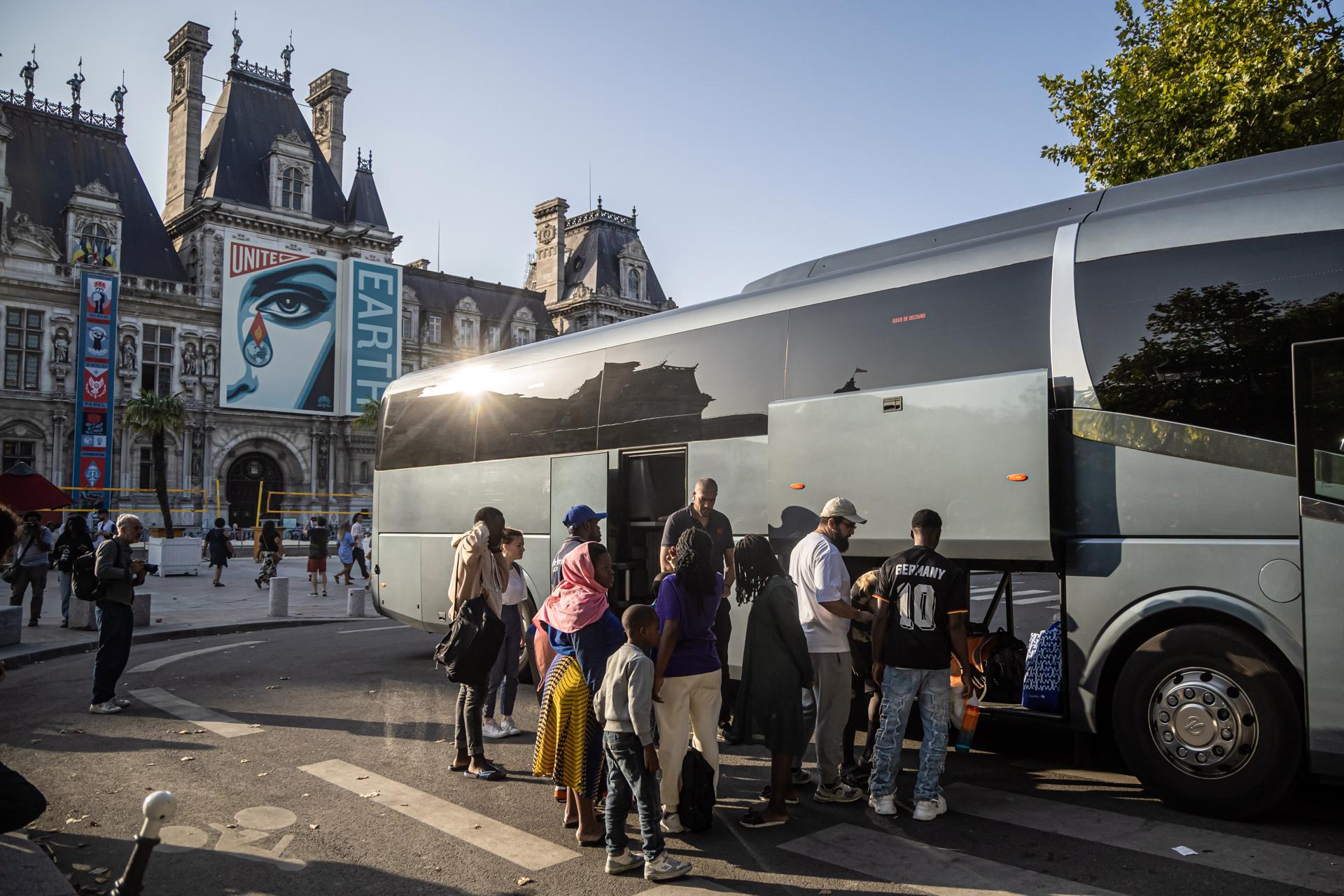 Un grupo de migrantes se prepara para subir a un autobús tras ser evacuados de un campamento improvisado frente al Ayuntamiento de París, Francia, el 12 de agosto de 2025.  EFE/EPA/CHRISTOPHE PETIT TESSON

