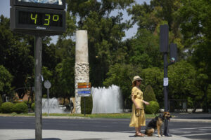 Una mujer pasea a su perro cerca de un termómetro de Sevilla que marca 43 grados, este 3 de agosto. EFE/ Raúl Caro.