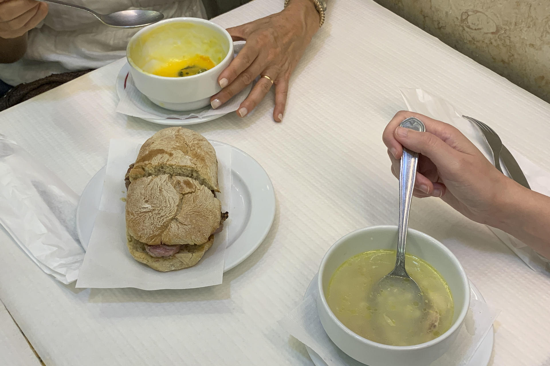 Dos comensales degustan caldo de gallina y sopa de nabo en la cafetería Herculano de Lisboa, donde las sopas del día en caliente son uno de los platos fijos en el menú durante todo el año, incluido el verano. EFE/Carlos Caselles