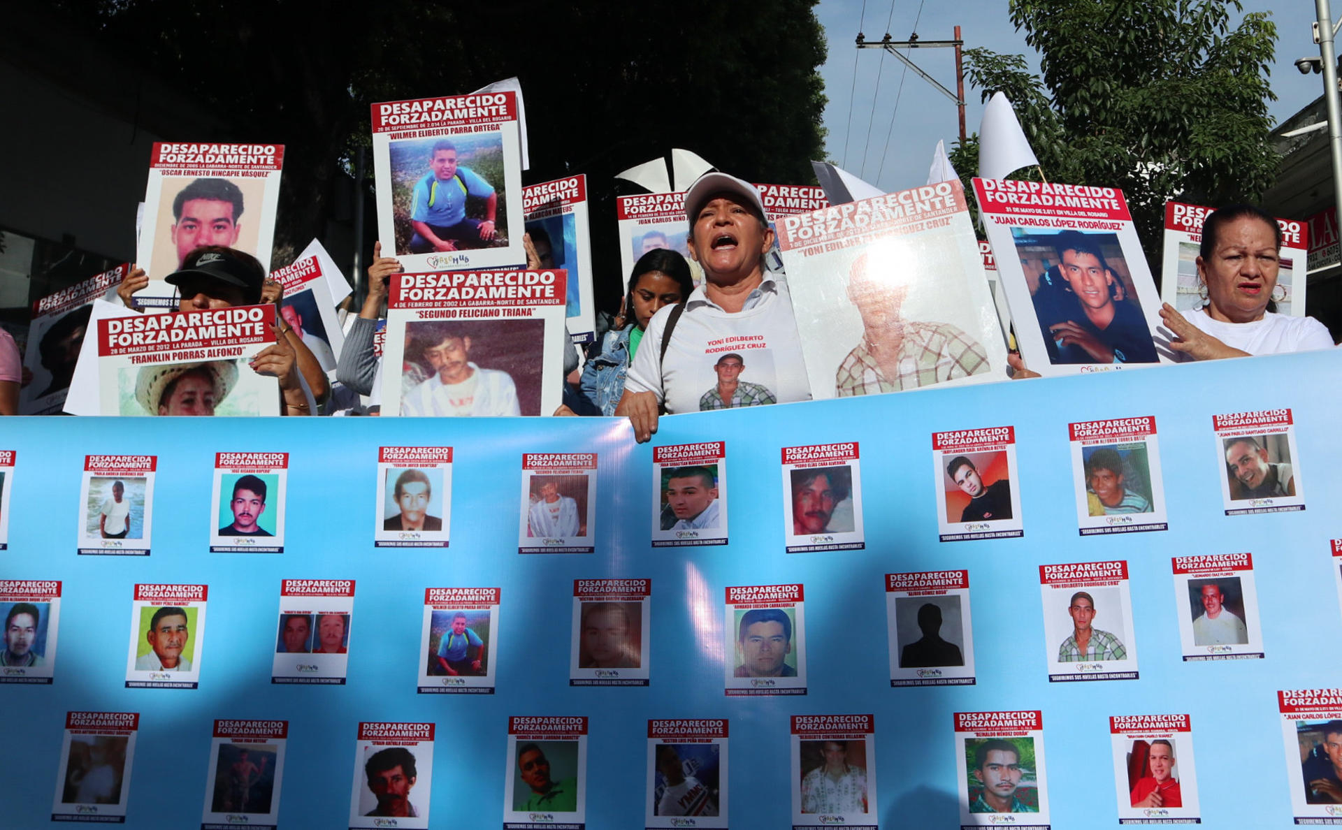 Familiares de víctimas de desaparición forzada protestan este sábado sosteniendo carteles con fotos de sus allegados desaparecidos, en Cúcuta (Colombia). EFE/Mario Caicedo