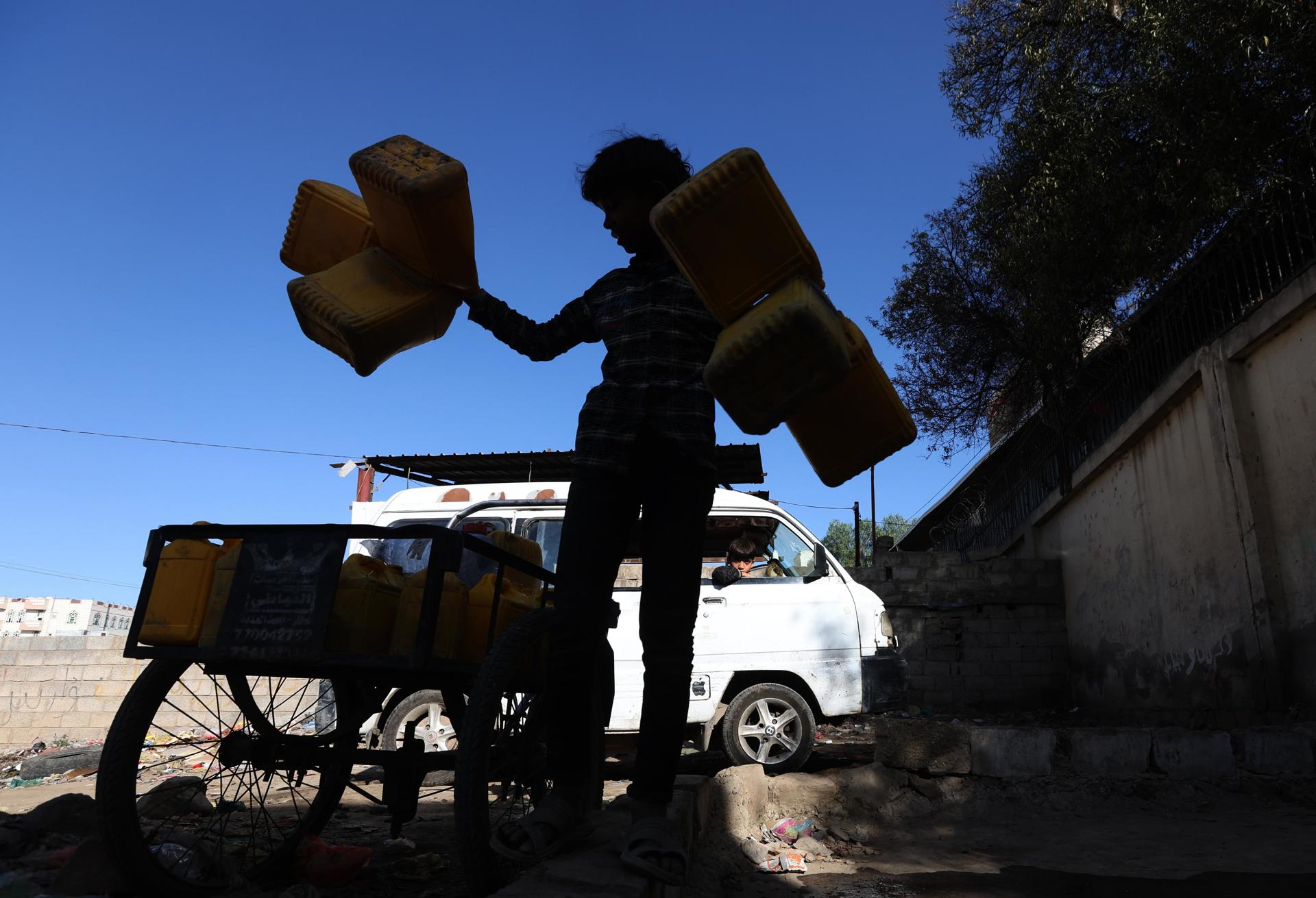 Fotografía de archivo de un joven sosteniendo galones de agua. EFE/YAHYA ARHAB