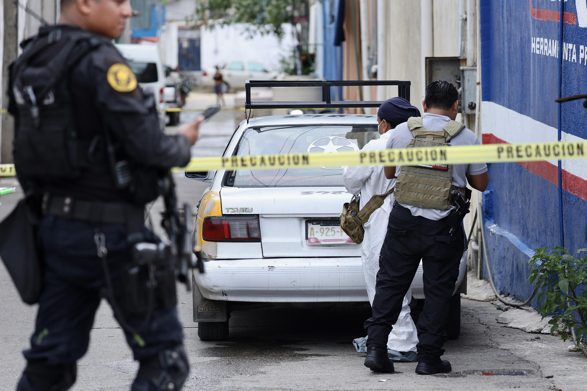 Peritos forenses trabajan en el lugar donde fueron encontrados dos cuerpos al interior de un taxi en Acapulco (México). EFE/ David Guzmán
