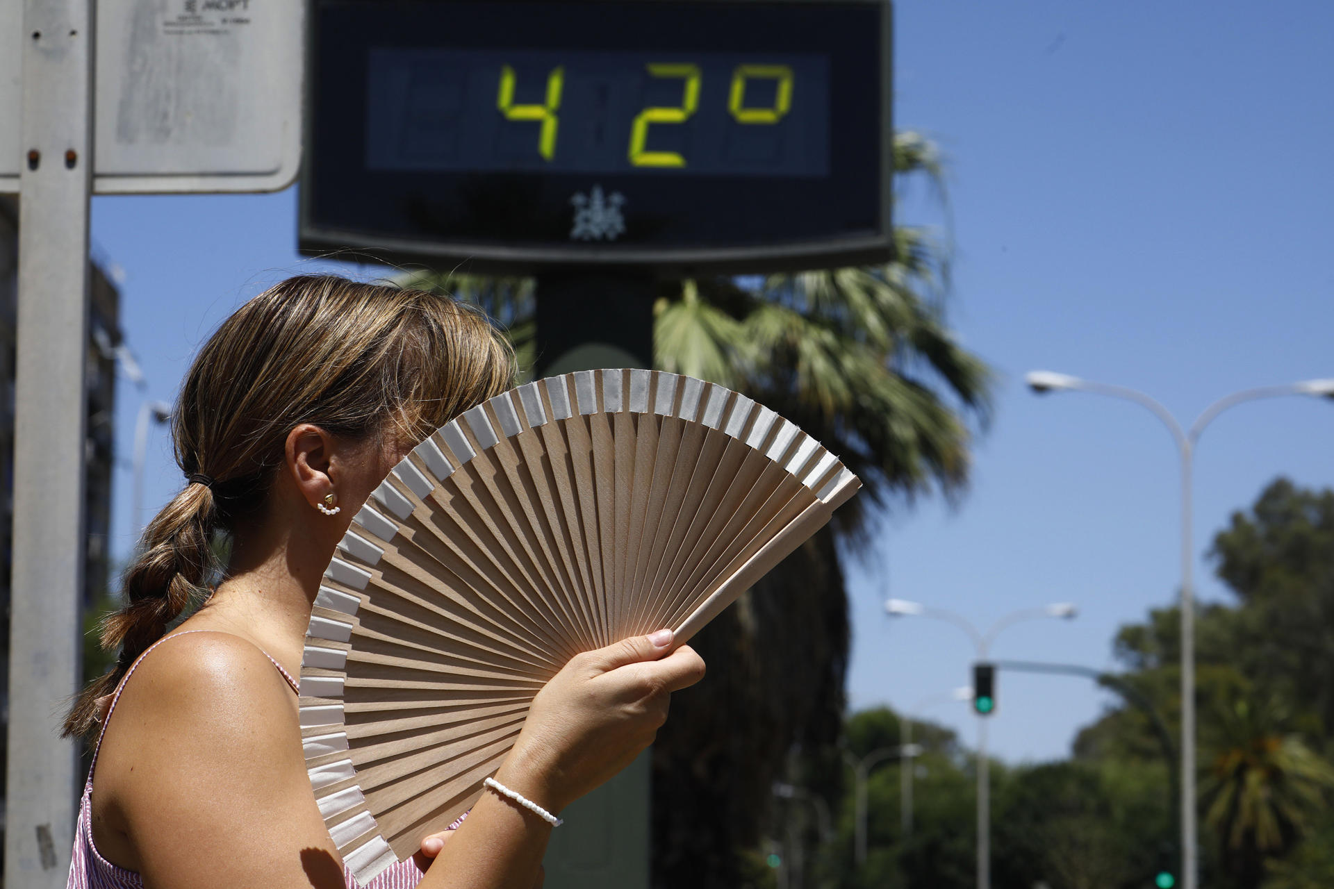 Una mujer se abanica mientras pasa por un termómetro de calle que marca 42 grados en Córdoba, en una imagen de archivo. EFE/Salas