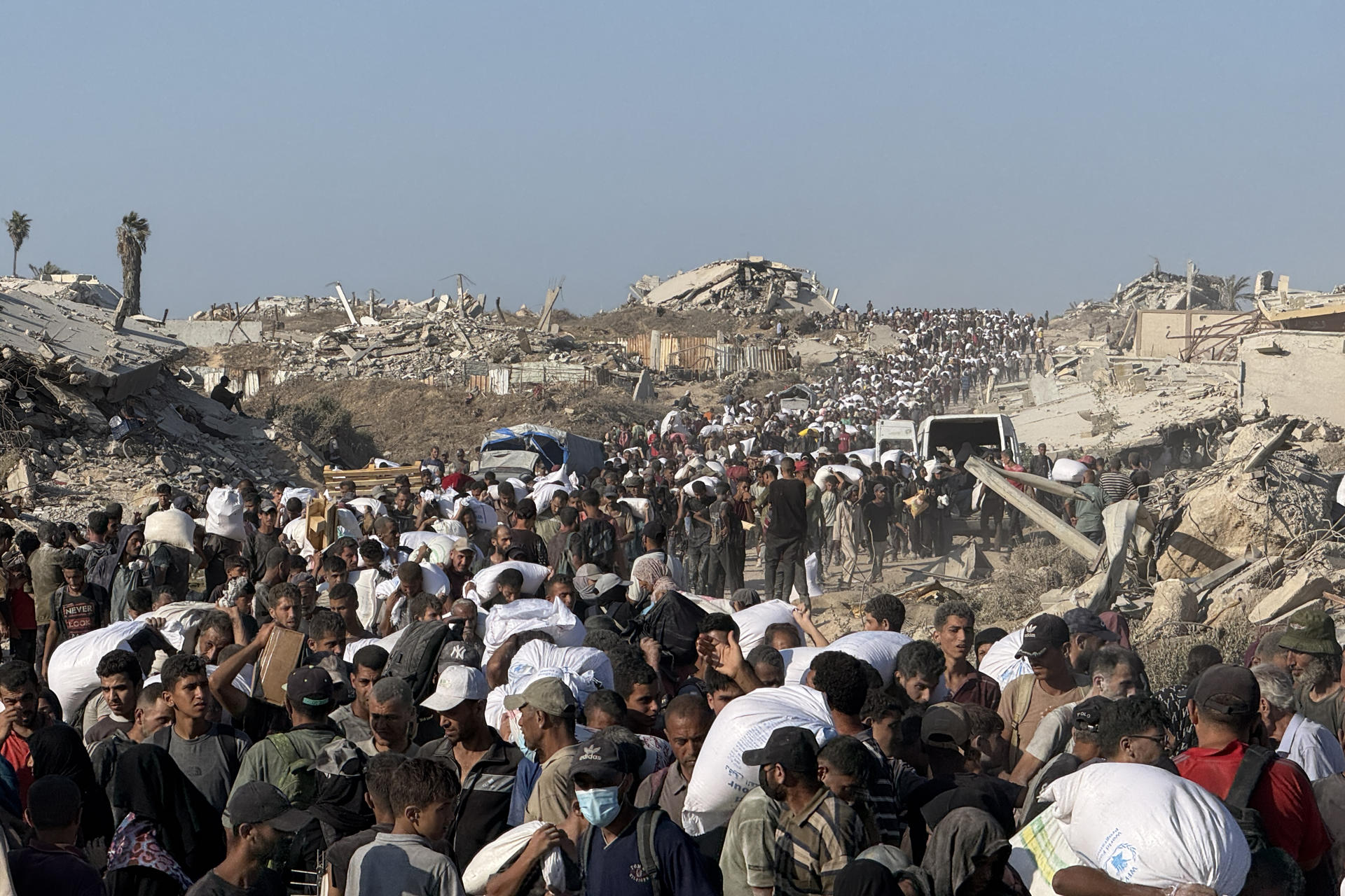ZIKIM (FRANJA DE GAZA), 07/08/2025.- Miles de personas acuden a una zona militarizada cerca del cruce de Zikim, en el norte de la Franja de Gaza, para hacerse con harina del Programa Mundial de Alimentos. Son las dos de la tarde. Bajo el calor abrasador de Gaza, miles de personas caminan kilómetros en dirección a la frontera de Zikim, en el extremo noroeste de la Franja, para intentar hacerse con harina de uno de los camiones que entran cada día por allí. Algunos vuelven cubiertos de sangre, otros muertos y, los afortunados, cargados de sacos del preciado "oro blanco". EFE/ Ahmad Awad