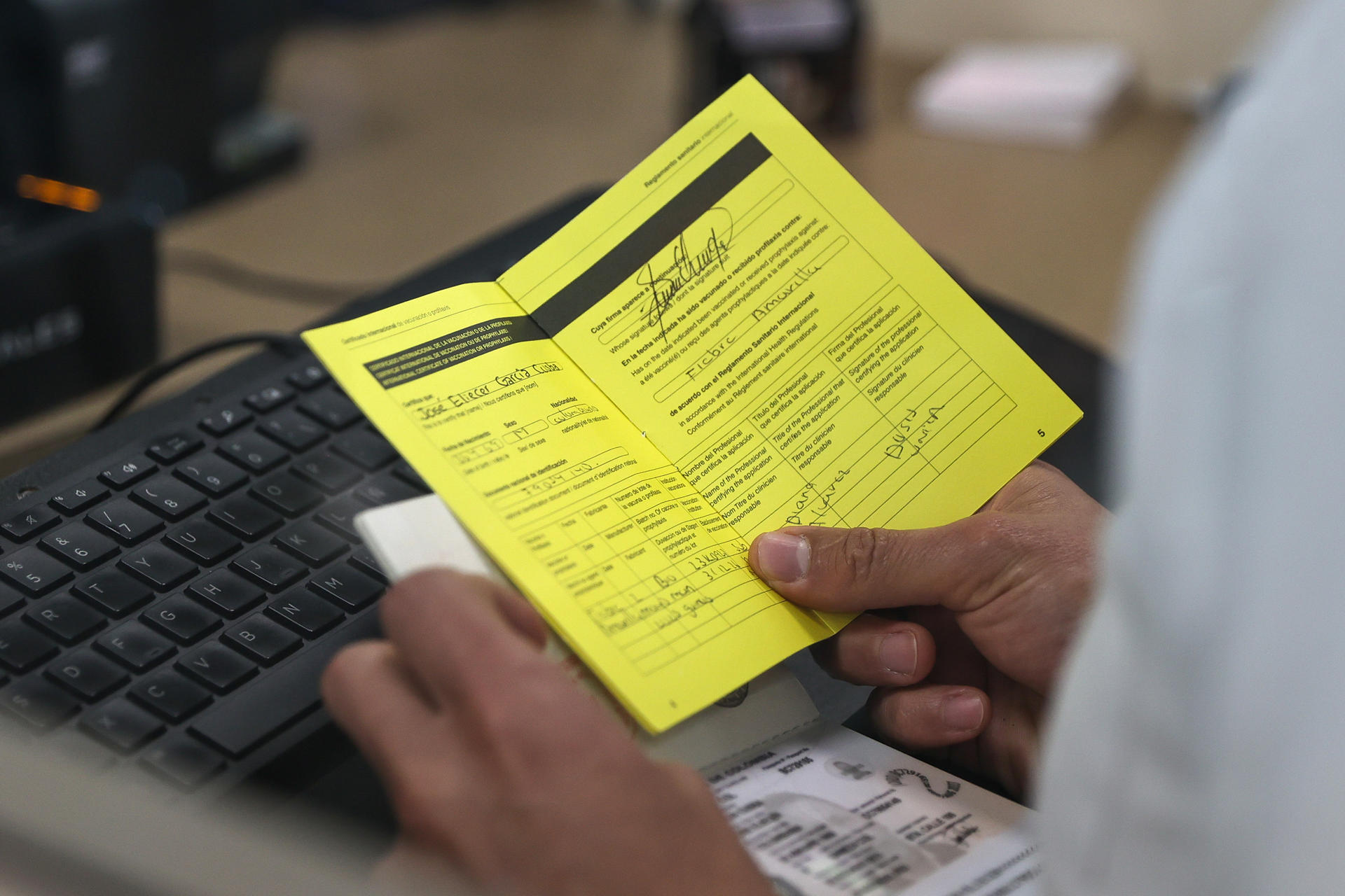Fotografía de archivo del detalle de las manos de un funcionario ecuatoriano de Migración al revisar un certificado de vacunación contra la fiebre amarilla, en el Aeropuerto Internacional Mariscal Sucre, en Quito (Ecuador). EFE/José Jácome