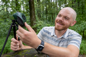 Brent Pease, profesor adjunto de la Facultad de Silvicultura y Horticultura de la Universidad del Sur de Illinois muestra un BirdWeather, un dispositivo resistente a la intemperie con micrófonos, Wi-Fi, GPS, sensores ambientales e inteligencia artificial. Gracias a esta aplicación de ciencia ciudadana se ha documentado que la contaminación lumínica, que afecta a casi la cuarta parte de la superficie de la Tierra, está provocando que las aves de todo el mundo canten más tiempo cada día, prolongando sus vocalizaciones una media de 50 minutos. Crédito: Foto de la Universidad del Sur de Illinois en Carbondale por Russell Bailey.