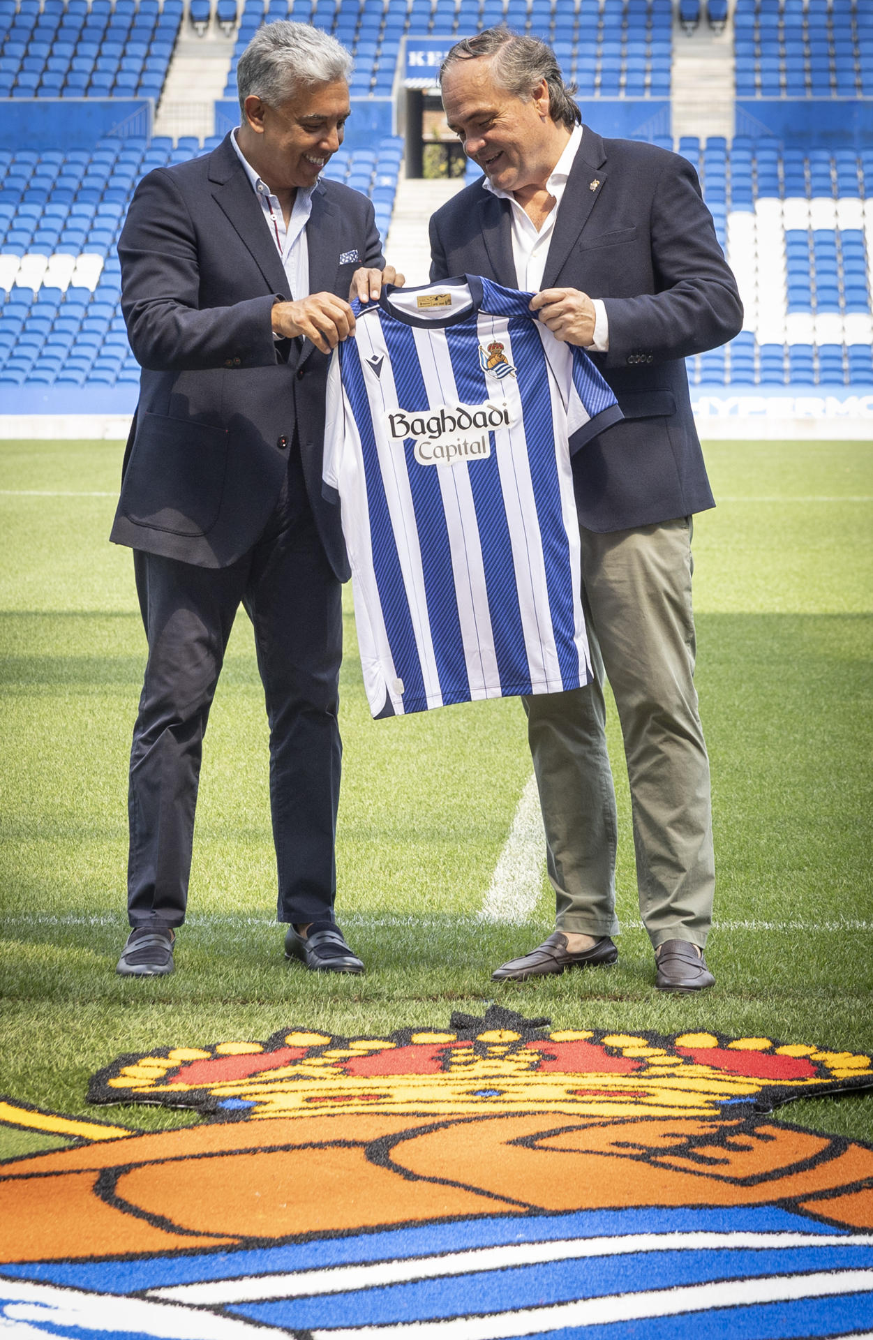 El presidente de la Real Sociedad, Jokin Aperribay (d), y el presidente y fundador de Baghdadi Capital, Baihas Baghdadi, posan este jueves durante la presentación de este compañía financiera como nuevo patrocinador del club blanquiazul. EFE/Javier Etxezarreta
