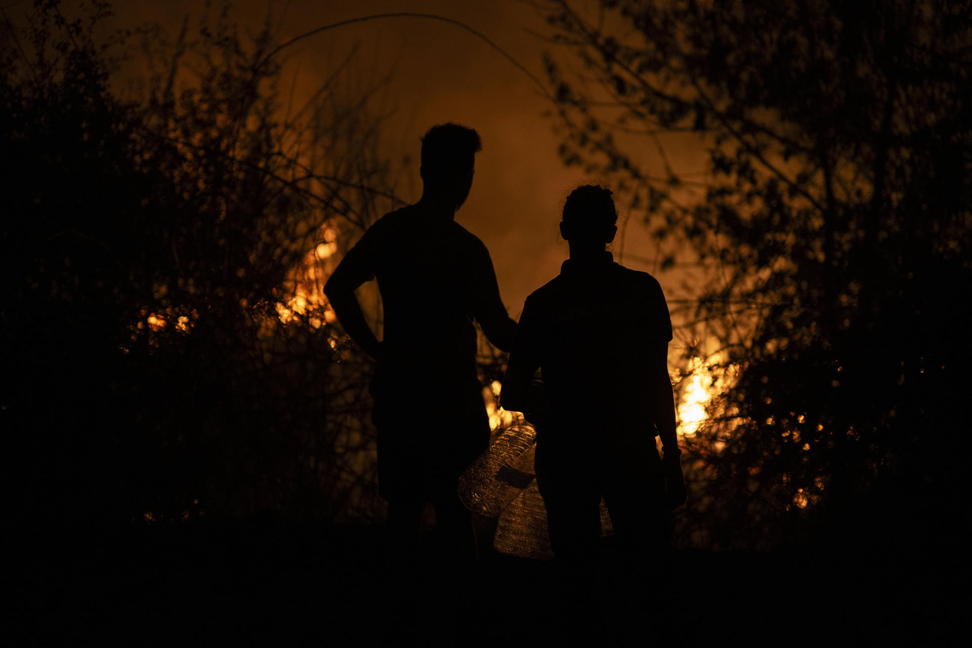 Dos personas observan la evolución del incendio forestal en A Rúa (Ourense). EFE/ Brais Lorenzo