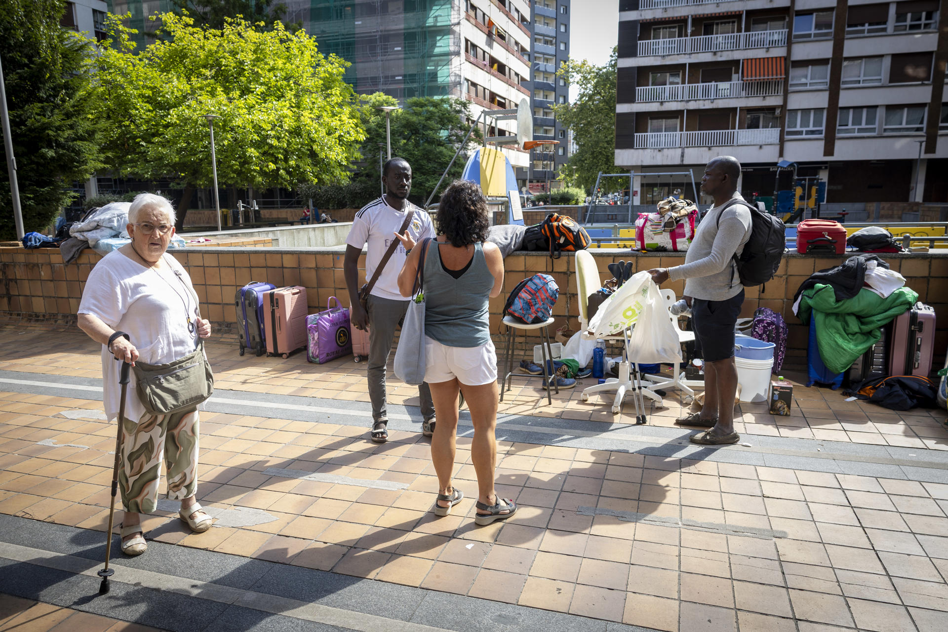 Los migrantes, en su mayoría de Mali, que viven en la calle en el barrio donostiarra de Amara Berri desde hace semanas conversan con vecinos de la zona mientras esperan en su campamento improvisado. La Diputación y el Ayuntamiento de San Sebastián va a alojar en un recurso de la localidad de Oñati (Gipuzkoa), "de manera excepcional" y "ante la falta de respuesta por parte del Gobierno español".EFE/Javier Etxezarreta

