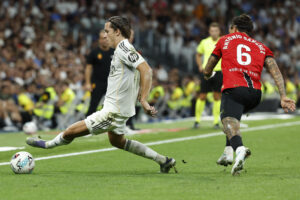 El defensa del Real Madrid Álvaro Carreras (i) controla el balón junto a Antonio Sánchez, del Mallorca, durante el partido de la tercera jornada de LaLiga entre el Real Madrid y el RCD Mallorca, en el estadio Santiago Bernabéu. EFE/Chema Moya