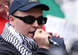 Liam O'Hanna de Kneecap habla con sus seguidores al salir del Tribunal de Magistrados de Westminster en Londres, Reino Unido, 20 de agosto de 2025. El músico, que se presenta bajo el nombre artístico de Mo Chara y también es conocido como Liam Og O hAnnaidh, compareció ante el tribunal acusado de terrorismo por exhibir una bandera de Hezbollah en un concierto de noviembre de 2024. Ahora enfrenta una espera de un mes para saber si se desestimarán los cargos. (Terrorismo, Terrorista, Reino Unido, Londres, Hizbulá/Hezbolá) EFE/EPA/NEIL HALL