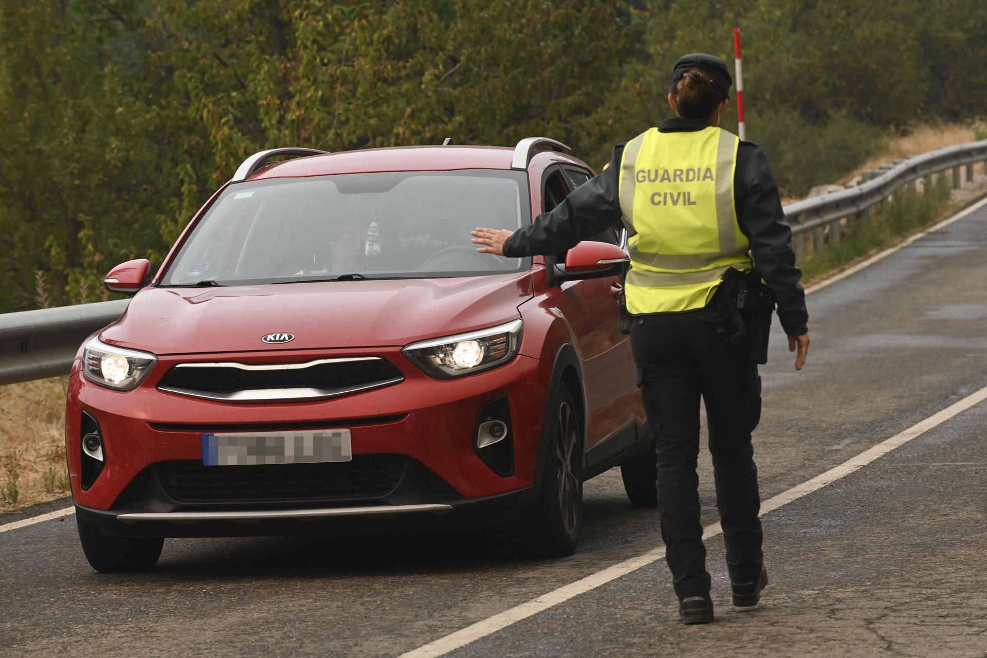 Una agente de la Guardia Civil impide el paso a un coche ante el incendio que amenaza la vertiente leonesa del Parque Nacional de Picos de Europa, iniciado en Barniedo de la Reina e impulsado por el viento y las altas temperaturas. EFE/J.Casares