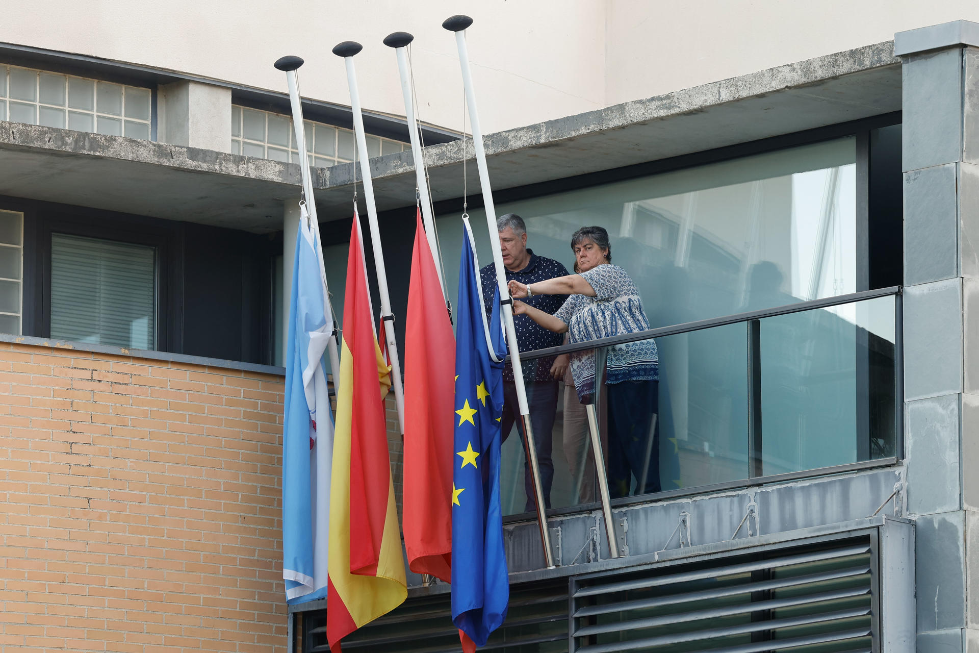 Empleados municipales colocan las banderas a media asta este viernes en el Ayuntamiento de Zizur Mayor, antes de la concentración de repulsa por el fallecimiento de una vecina de la localidad de 78 años, tras la declaración oficial del caso como un episodio de violencia de género. EFE/Villar López