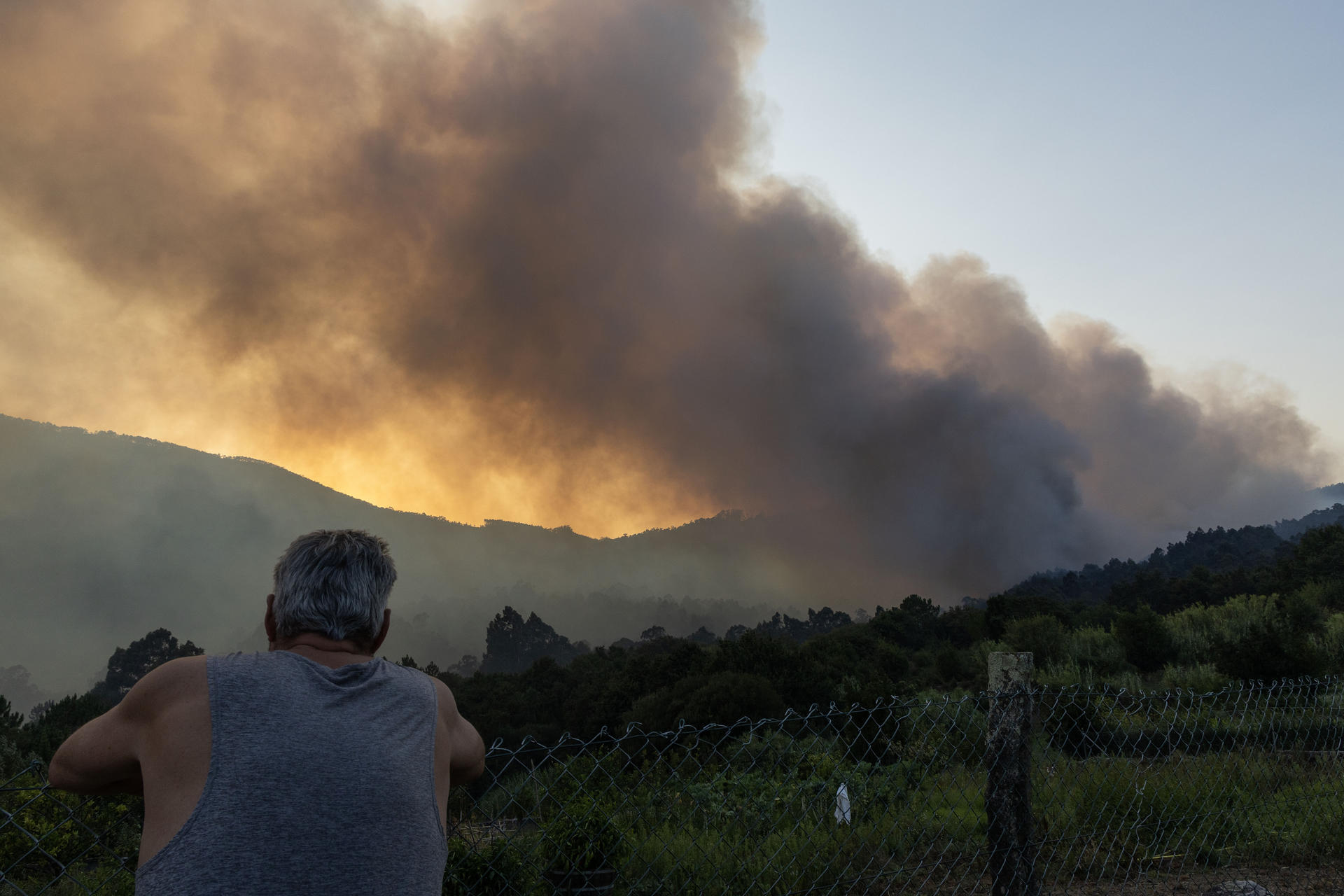 Vecinos observan el avance del fuego en Vilaboa, parroquia de Santa Cristina de Cobres, que se inició a primera hora de la tarde de este jueves y se decretó el nivel 2 por la cercanía del fuego al núcleo de Vilar. EFE/ Salvador Sas