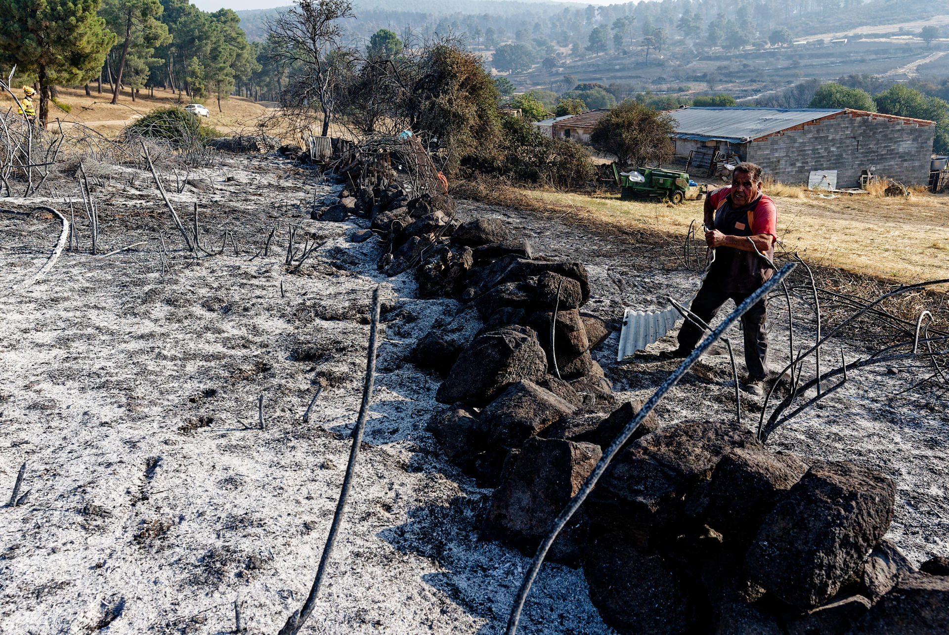 Un hombre trabaja en un muro de su explotación ganadera afectada por el incendio en Las Navas del Marqués (Ávila), este domingo. El incendio que el viernes se declaró en el municipio abulense de San Bartolomé de Pinares y se extendió a Las Navas del Marqués se encuentra en una situación "favorable", después de una noche en la que han seguido produciéndose "pequeñas reactivaciones" en el interior del perímetro, que han sido controladas. EFE/ Raúl Sanchidrián