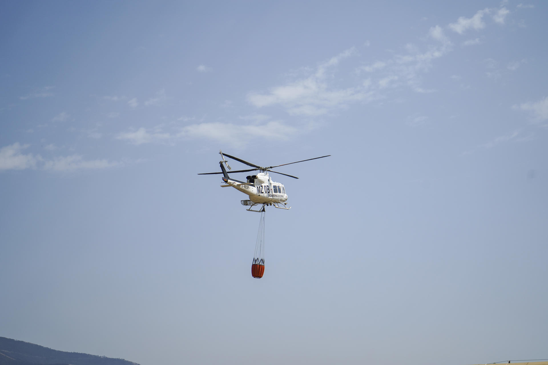Fotografía tomada desde el Valle del Jerte (Palacio de la Cereza, en Valdastillas) de un helicóptero que se dirige al frente de un incendio que avanza hacia Segura de Toro, este sábado. Seis incendios se mantienen activos y sin control esta tarde en Extremadura, sin situaciones destacables con respecto a esta mañana, salvo que los efectivos de la Unidad Militar de Emergencia (UME) que actuaban en el incendio de Llerena se han traslado con sus camiones hasta Aliseda, donde se consideran más necesarios. EFE/Eduardo Palomo
