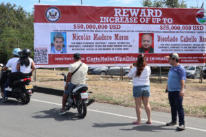 Personas observan una valla con la imagen del presidente de Venezuela, Nicolás Maduro, y del ministro de Relaciones Interiores, Justicia y Paz de Venezuela, Diosdado Cabello, este sábado en Villa del Rosario (Colombia). EFE/ Mario Caicedo