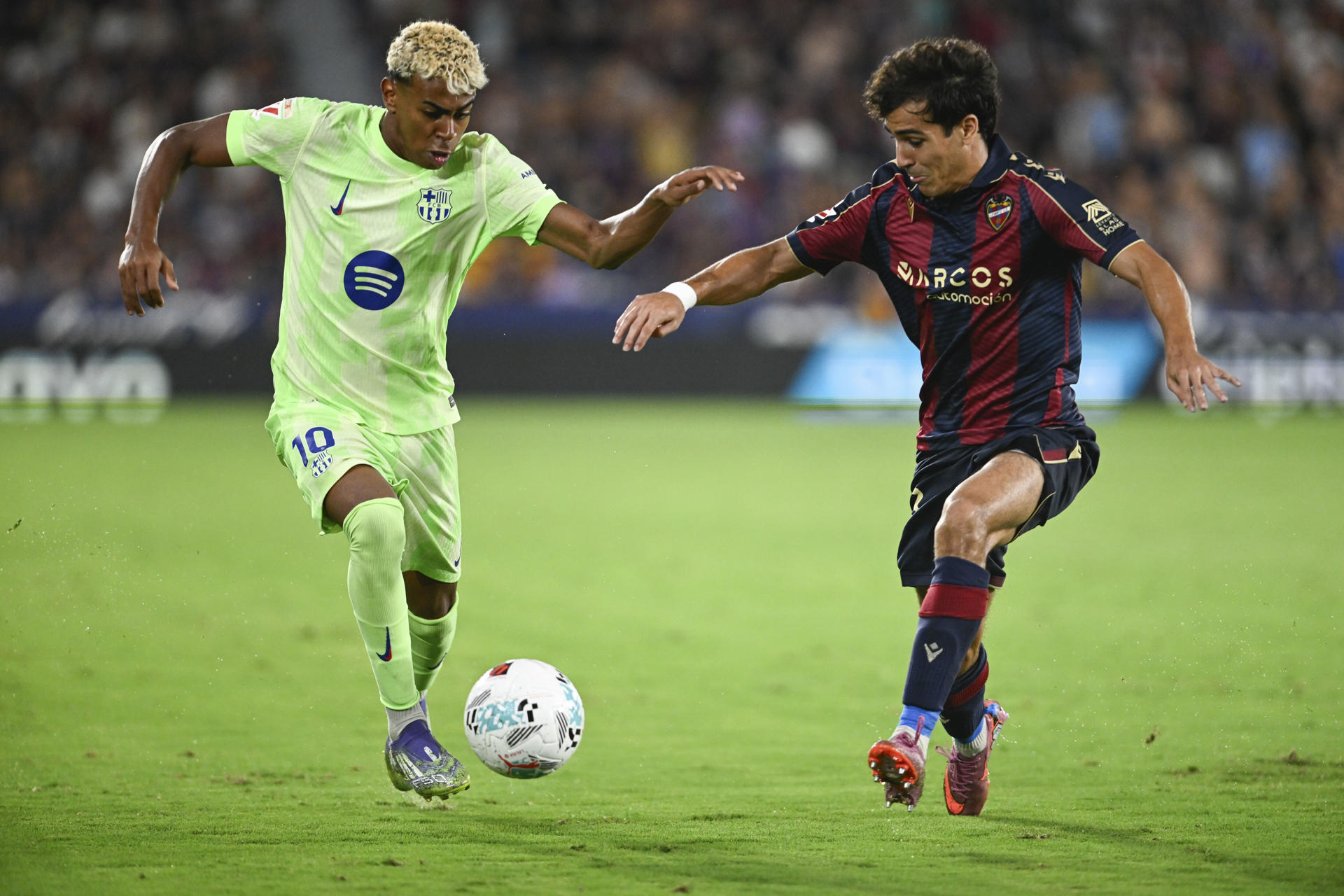 El delantero del Barcelona Lamine Yamal (i) trata de escapar de Manu Sánchez, del Levante, durante el partido de LaLiga de fútbol que Levante UD y FC Barcelona disputaron en el estadio Ciutat de Valencia. EFE/Andreu Esteban