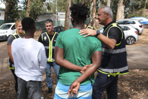 Los policías nacionales Víctor (d), Manuel, Sandra (i) y Daniel (3i), quienes participaron del rescate de los migrantes cuyo cayuco volcó a finales del mes de mayo en el puerto de La Restinga en El Hierro, visitan a dos de los supervivientes, Habib (2i) y Amara (c), en el exterior del Centro de Primeras Llegadas de Las Raíces en Tenerife, donde se encuentran actualmente. EFE/Alberto Valdés