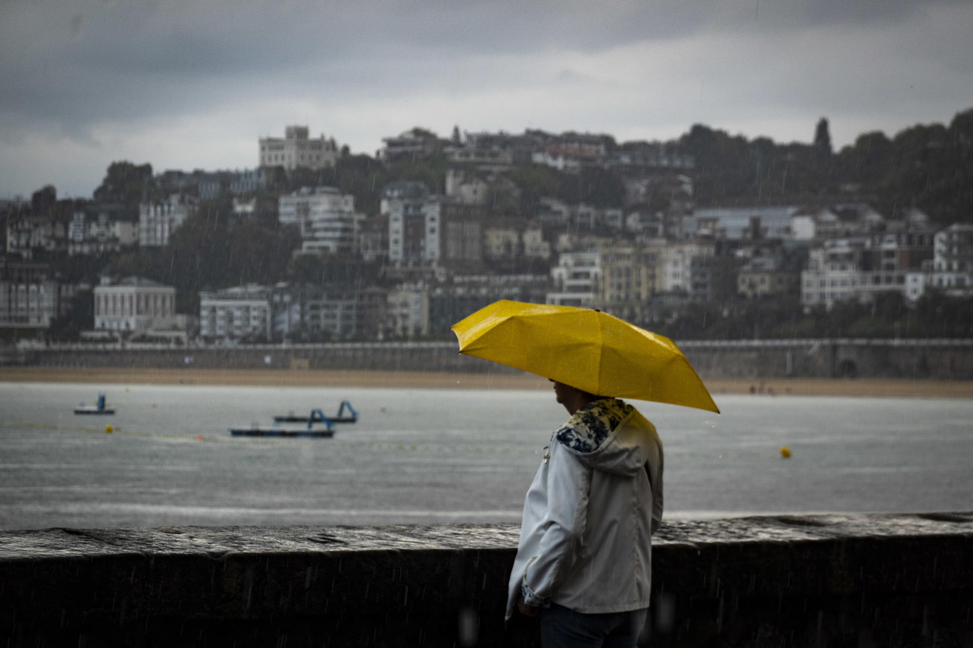 Una mujer observa el mar este miércoles en San Sebastián. Los cielos del País Vasco se presentan hoy nubosos, caerán chubascos débiles, que en la vertiente cantábrica podrían ser fuertes y tormentosos, las temperaturas mínimas se mantendrán estables o bajarán ligeramente y el viento soplará flojo a moderado del oeste, y se fijará durante la mañana a noroeste. EFE/Javier Etxezarreta