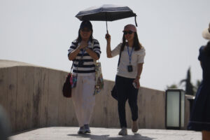 Dos personas se protegen del sol con un paraguas para aliviar las altas temperaturas este domingo en Córdoba. EFE/Salas