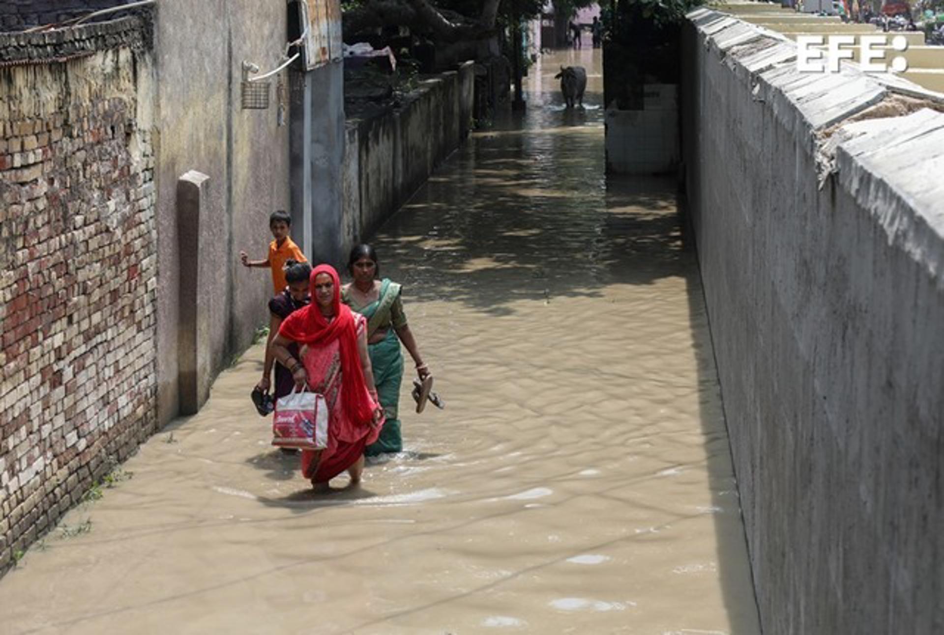 Habitantes de Nueva Delhi caminan por las aguas desbordadas del río Yamuna. EFE/EPA/RAJAT GUPTA