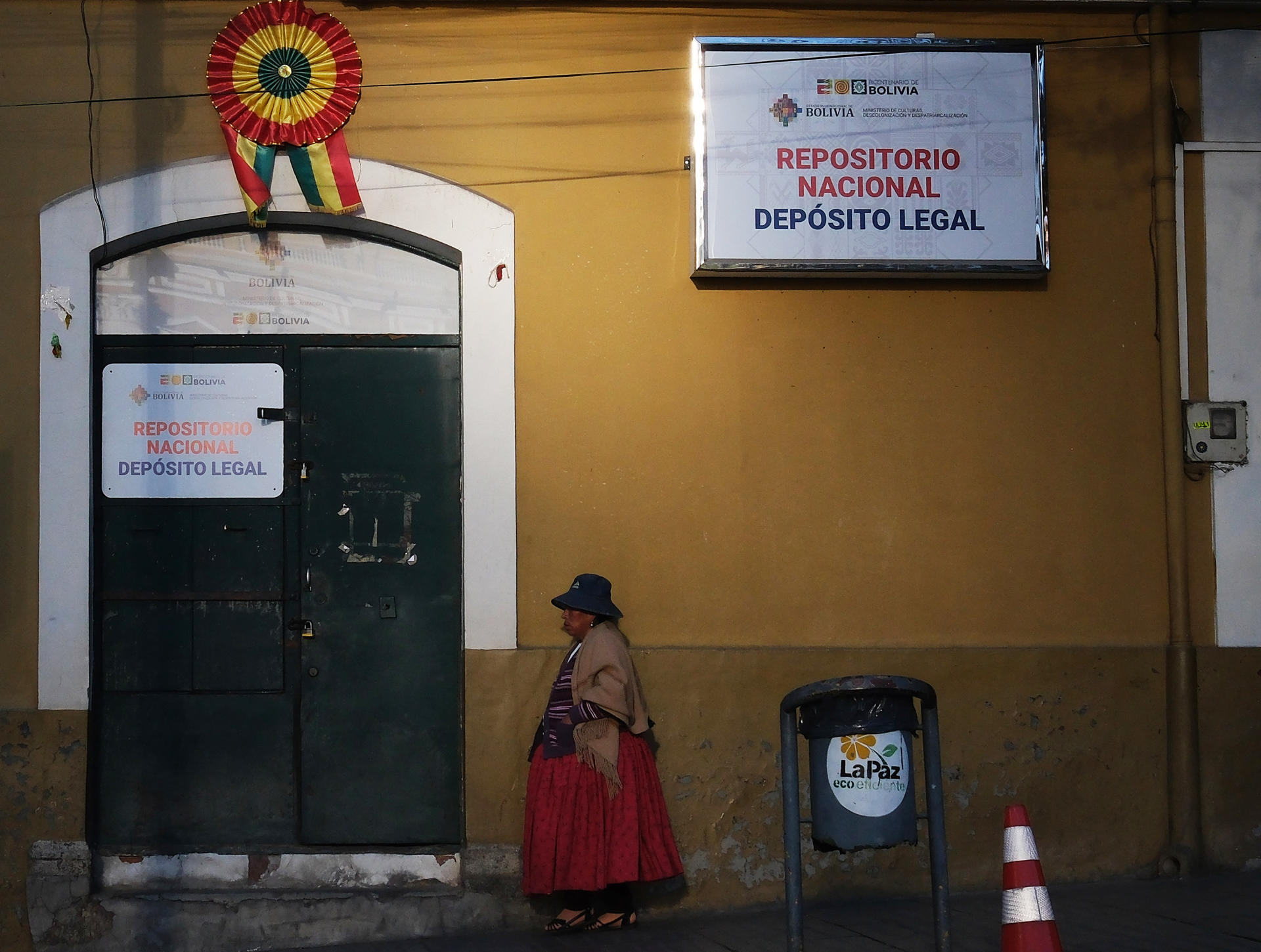Una mujer aimara camina frente a una casa adornada con banderas de Bolivia este lunes, en La Paz (Bolivia). EFE/Luis Gandarillas