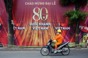 Fotografía de archivo, tomada el 21/08/2025, que muestra a un hombre en motocicleta pasando frente a un cartel que adorna una calle de Hanoi, con motivo del Día Nacional de Vietnam y el 80 aniversario de la Revolución de Agosto. EFE/EPA/LUONG THAI LINH