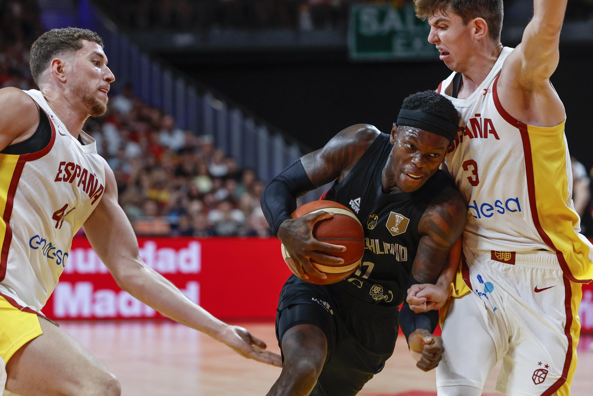 El base de la selección alemana de baloncesto Dennis Schroeder (c) trata de superar al español Sergio de Larrea (d), durante el partido amistoso que España y Alemania disputan este jueves en el Madrid Arena. EFE/Mariscal
