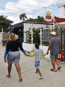 Fotografía del 2 de agosto de 2025 de personas pasando frente a la cafetería Burguer Queen, en La Habana (Cuba). EFE/ Ernesto Mastrascusa