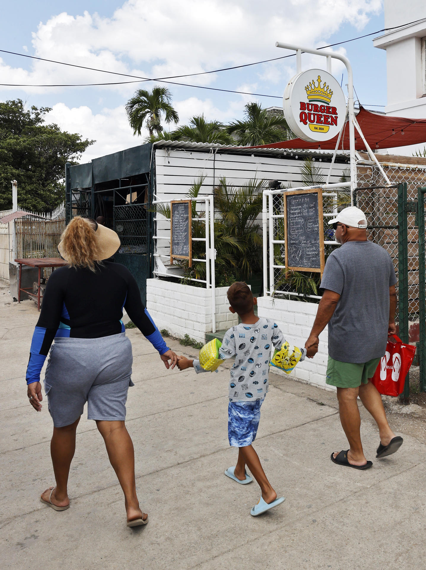 Fotografía del 2 de agosto de 2025 de personas pasando frente a la cafetería Burguer Queen, en La Habana (Cuba). EFE/ Ernesto Mastrascusa