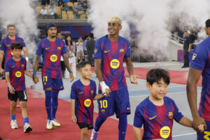 El jugador del Barcelona Lamine Yamal entra al campo de la mano de un niño, antes del tercer partido de la pretemporada del equipo azulgrana ante el Daegu coreano, el pasado lunes en Seúl. EFE/ Jeon Heon-kyun