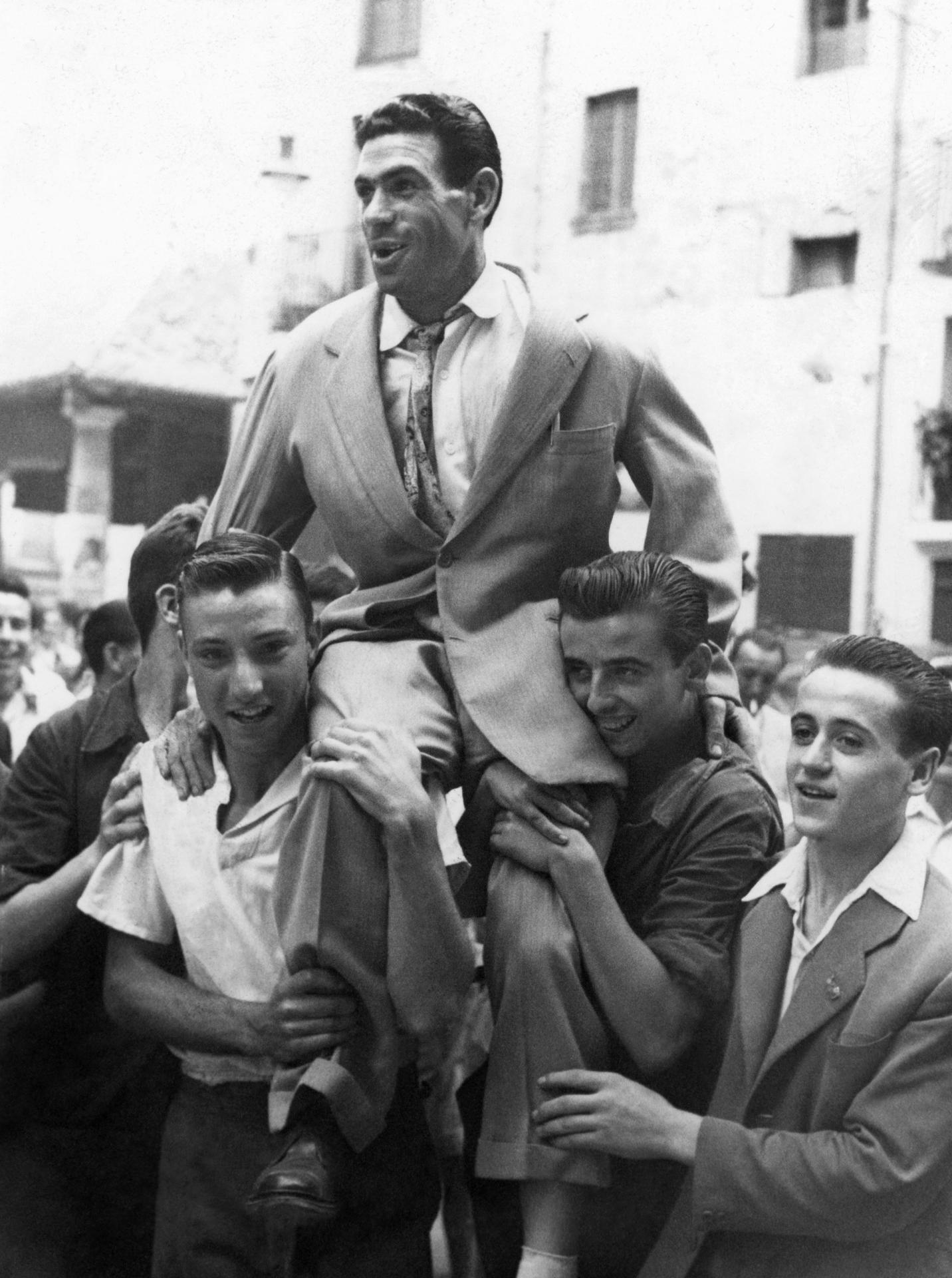 El ciclista español Bernardo Ruiz, tercer clasificado en el Tour de 1952, es llevado a hombros por un grupo de aficionados a su llegada a Barcelona. EFE/Pérez de Rozas/archivo
