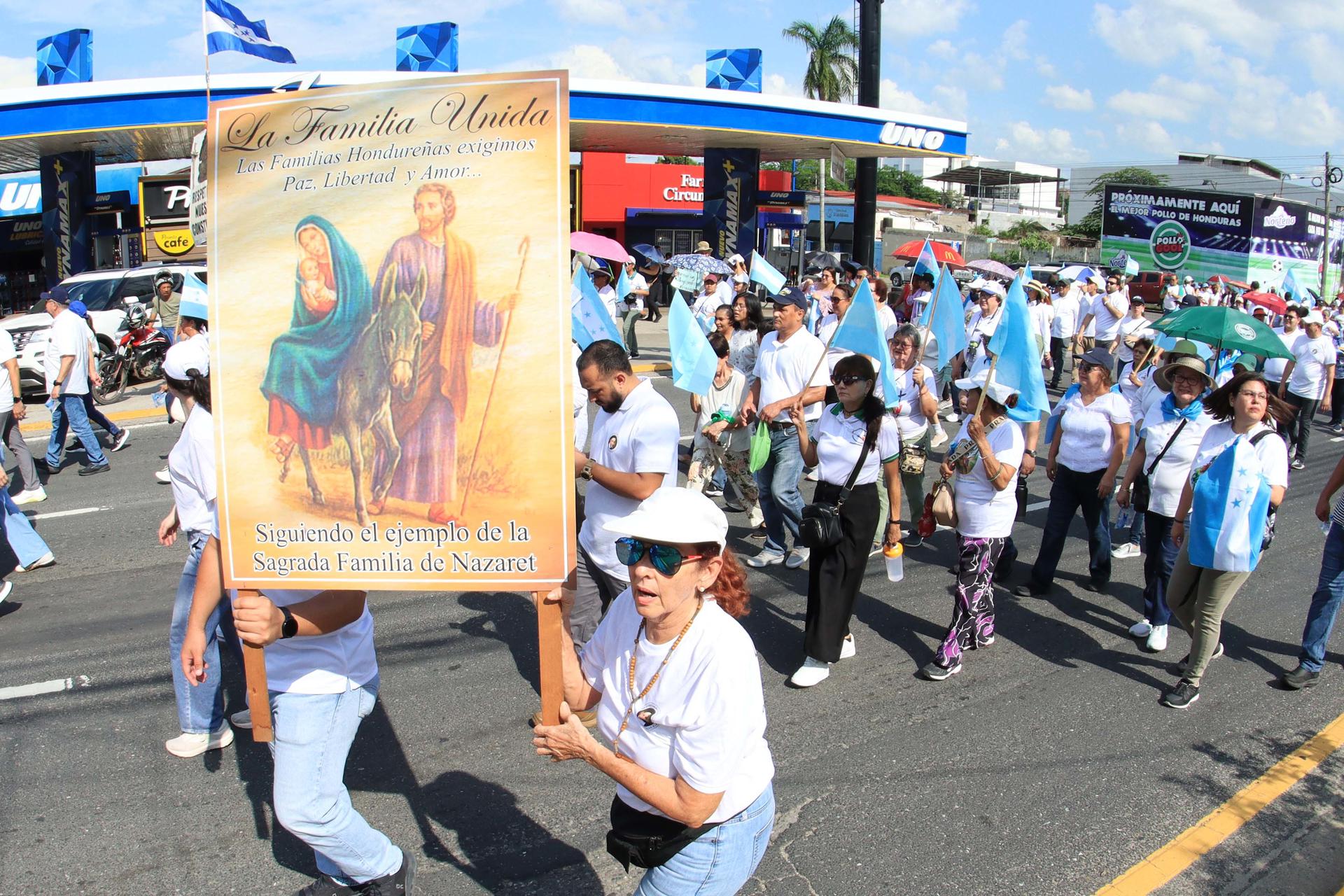 Una mujer sostiene un cartel con la imagen de la Sagrada Familia durante una marcha por la paz este sábado, en San Pedro Sula (Honduras). EFE/ Jose Valle
