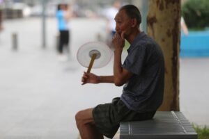 Un hombre se abanica para aliviar el calor en un barrio residencial en Pekín. EFE/ Wu Hong/Archivo