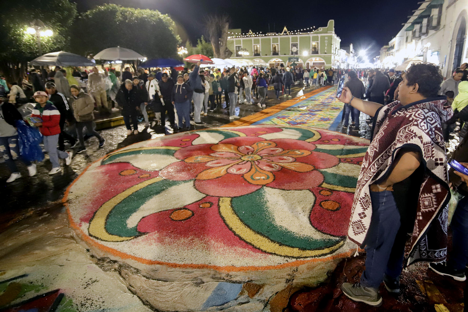Personas observan los tradicionales tapetes de flores de aserrín durante la 'Noche que Nadie Duerme' en honor a la Virgen de la Caridad este viernes, en Huamantla (México). EFE/ Hilda Ríos
