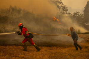 Un efectivo de la Unidad Militar de Emergencias (UME) y un vecino de la localidad de A Espasa trabajan durante el incendio forestal que permanece activo en Chandrexa de Queixa (Ourense), este martes. EFE/Brais Lorenzo