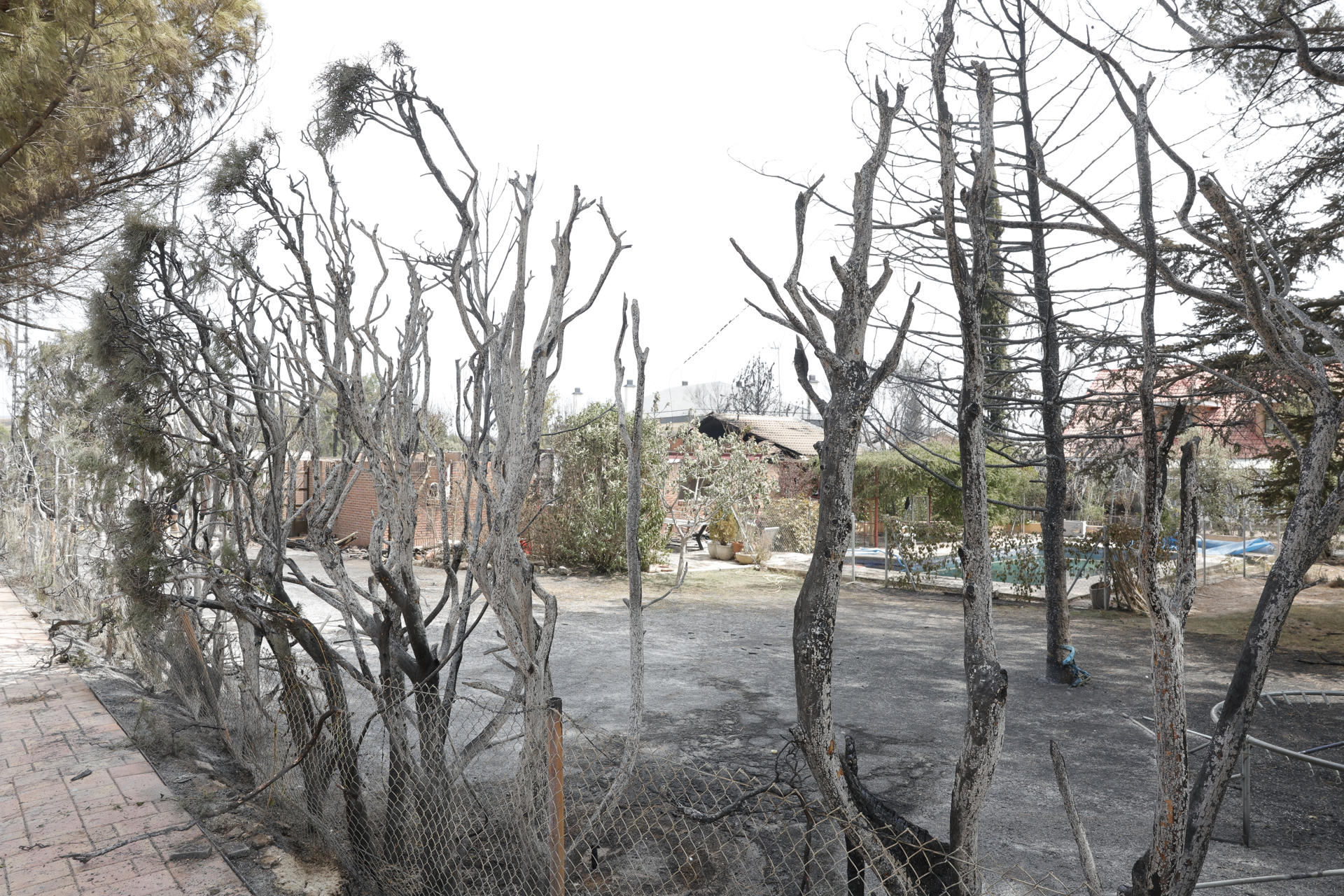 Vista de viviendas afectadas por el fuego en la urbanización Soto de Viñuelas mientras continúan las labores de extinción del incendio en Tres Cantos, Madrid, el cual ya está perimetrado. EFE/ Zipi
