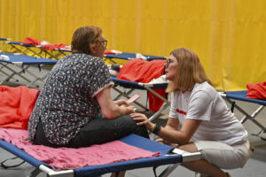 Una psicóloga de Cruz Roja habla con una mujer desalojada de un pueblo de Palencia por el avance del fuego de Canalejas, desde la provincia de León, que ha pasado la noche en el polideportivo de Saldaña. EFE/ Almudena Álvarez